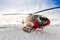 Red rescue helicopter lands standing in snowy mountains