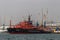 Red rescue ship stands at the mooring wall of a large sea city