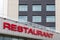 Red restaurant title on modern gray tiled building facade.