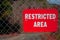 Red Restricted Area Sign on a Chain Link Fence
