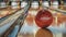 Red retro bowling ball on a wooden lane with pins in the background.