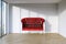 Red retro leather sofa in modern interior room with panoramic wi