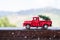 Red retro small car carrying christmas tree in the mountain in snowfall. Winter holiday concept.