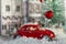 Red retro toy car. Winter snowy European street decorated for Christmas