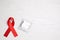 Red ribbon and condom on white wooden background, flat lay with space for text. AIDS disease awareness
