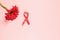 Red ribbon with a red gerbera flower on a pink background. The concept of medicine and human health care. World breast