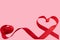 Red ribbon in the shape of a heart on a pink background. The concept of Valentine`s Day. A postcard for expressing feelings. Free