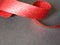 Red ribbon, spiral coil on black paper background.