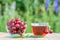 Red ripe cherry fruits with peduncles in glass bowl and cup of tea