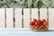 Red ripe cherry tomatoes on wicker basket in garden. Wooden table on background of wooden fence and tomato plant. Side view. Copy