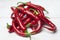 Red and ripe hot chillies arranged on a white table.