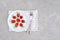 Red ripe strawberries berry on white plate, cutlery and red alarm clock on gray stone background table. Top view, flat lay, copy