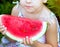 Red ripe watermelon in the hands little caucasian girl, large slice. Childhood. Happiness. Summer. Recreation. Healthy eating