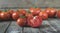 Red and ripped tomato in front of group of tomatoes on wooden ta
