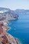 Red rocky coast of Santorini, Greece, with many boats in the blue sea