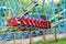 Red rollercoaster riding on blue and yellow railroad against blue sky in the amusement park