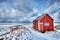 Red rorbu house shed on beach of fjord, Norway