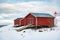 Red Rorbuer houses and lighthouse in Lofoten Islands, Norway. Snowy landscape