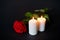 Red rose and burning candles over black background