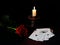 Red rose, ceramic candlestick with burning white wax candles and a deck of cards on a black background. Symbolic concept â€” life