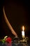 Red rose, feather in the inkwell and candle in the candlestick on a black background