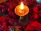 Red rose flowers over yellow background with diwali diya kept in the middle.