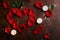 Red rose petals in heart shape with white candles on dark brown and golden background. Love, romance, anniversary, valentine`s day