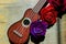 Red rose on a purple guitar ukulele neck and fretboard.