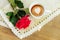Red rose on the rough table napkin with cup of coffe.Wooden table background.Top view