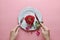 Red rose on white dish, Couple ring inside, with hand holding fork and knife, on pink background, Concept of Valentine`s Day