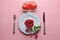 Red rose on white dish, with fork and knife, And couple heart in white basket, On pink background.