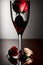 a red rose with white and red petals stands in a tall glass goblet