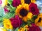 red roses are in bloom and bright yellow sunflowers are blooming bunched together