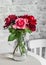 Red roses in a glass vase on the table in a cozy room. Beauty home interior still life