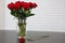 Red roses in glass vase with water and one rose next to vase on black table