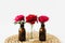 Red roses in glass vases on a wicker napkin on white background