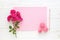 Red roses, pencil, macaroons and blank pink paper card on wooden background. Copy space, flat lay