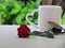 Red roses placed in front of white glass with heart-shaped handle on white table