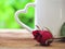 Red roses placed in front of white mug with heart-shaped handle on wooden table