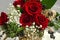 Red roses, surrounded by sprigs of white gypsophila,berries, and conifer twigs in a small wooden box