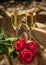 Red roses and two glasses of champagne on a background of gold brocade in honor of Valentine`s day wedding day