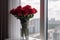 red roses in a vase on a windowsill, with the view of the city skyline behind