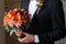 Red roses wedding bouquet in hands of the grrom