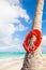 Red round life buoy hanging on the palm tree