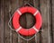 Red and round lifebuoy hanging on brown wooden wall
