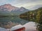 Red rowing boat in front of mirror image of Pyramid Mountain in Autumn, Rocky Mountains