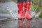 Red rubber boots are jumping into a big puddle