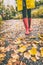 Red rubber boots woman walking in autumn leaves street in park. Fall fashion lifestyle