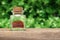 Red saffron spice on a green nature background. Aromatic saffron spice bottle on a wooden desk in a spring garden