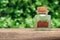 Red saffron spice on a green nature background. Aromatic saffron spice bottle on a wooden desk in a spring garden